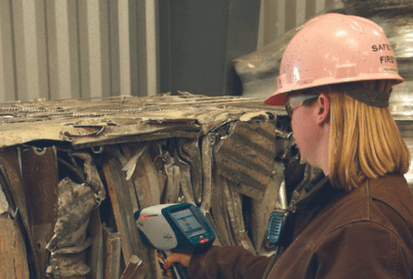 woman testing scrap steel with handheld xrf analyzer